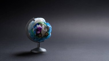 Globe made of garbage on a dark background. The concept of pollution of the planet with garbage. Copy space, selective focus on trash.