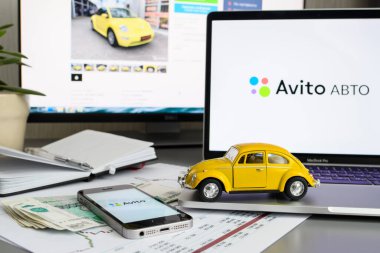 Vladimir, Rusya - Ocak 2022: Avito web sitesinin arka planında dizüstü bilgisayardaki sarı oyuncak araba. Avito servisi vasıtasıyla araba satma ya da satın alma fikri. Arabaya odaklan..