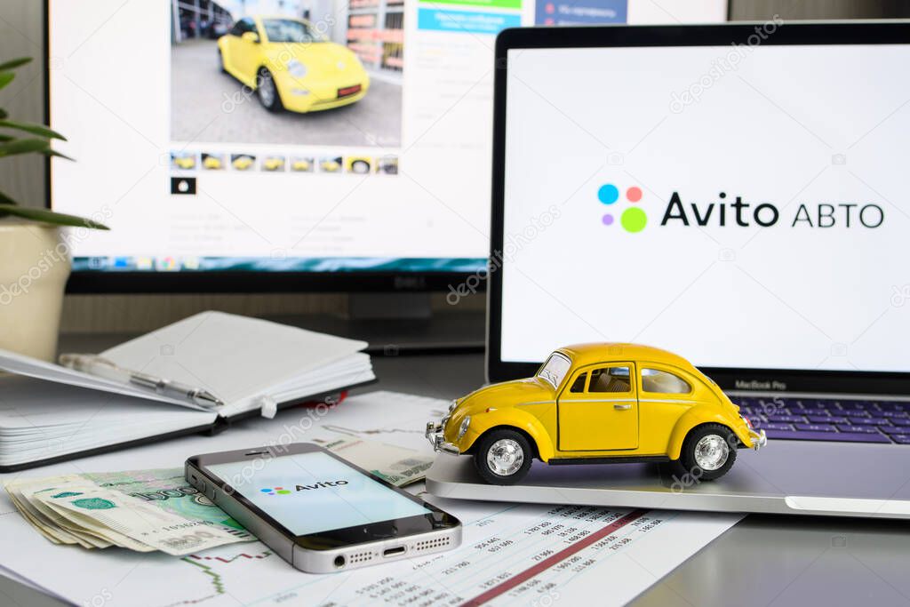 Vladimir, Russia - January 2022: Yellow toy car on a laptop against the background of the avito website. The concept of selling or buying a car through the Avito service. Selective focus on the car.