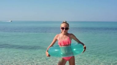 Duygusuz çemberli neşeli bir kız denizin arka planında dans ediyor. Kız döner ve geçen tekneye bakar.