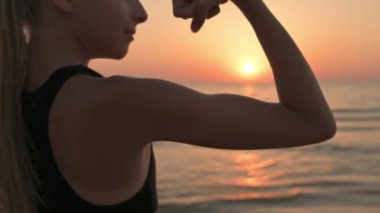 Genç bir kız beden eğitimi dersinden sonra gün batımında gücünü gösteriyor..