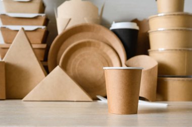 Farklı kağıt kapların arka planında tek kullanımlık kağıt bardak. Biyolojik ayrıştırılabilir sofra takımı konsepti. Kağıt bardağa seçici odaklanma.