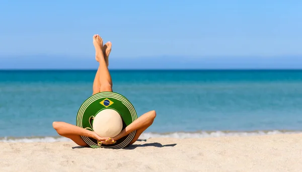 ブラジルの旗の色でわらの帽子のビーチで細い女の子 ブラジルのリゾート地での完璧な休暇の概念 帽子に集中しろ — ストック写真