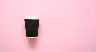 Pembe arka planda kahve için kağıt kıvrımlı koyu kahve fincanı. kopyalama alanı.
