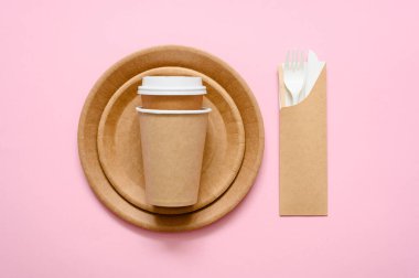 Pembe arka planda akşam yemeği için kağıt tabak takımı. Tabaklar. Kahve için fincan ya da çevre dostu kağıttan çay. Üst görünüm.