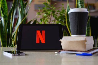 Vladimir, Rusya - Şubat 2022: Netflix uygulaması bir tablet üzerinde fast food 'un yanında. Yemek molasında Netflix izliyorsun. Logoya seçici odaklanma.