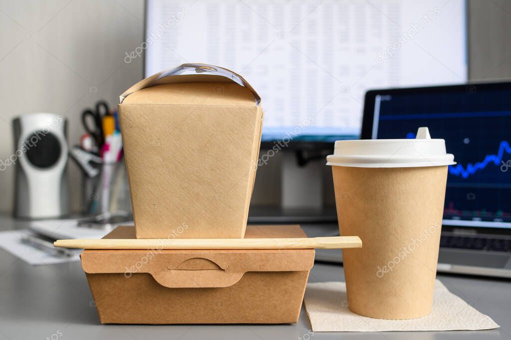 The concept of food delivery to the office. Paper packaging for food delivery for applying a logo on the background of the workplace. Advertisement for a food delivery service.