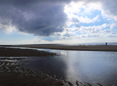Sylt Adası 'ndaki Westerland ana plajı. Gün batımında manzara, bulutlu gökyüzü, ufuk ve alçak gelgitte yansımalar..