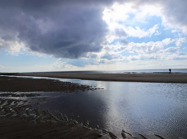 Sylt Adası 'ndaki Westerland ana plajı. Gün batımında manzara, bulutlu gökyüzü, ufuk ve alçak gelgitte yansımalar..