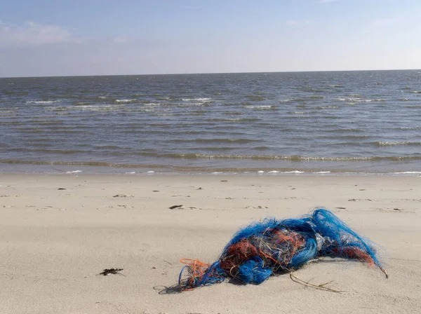 Sahilde çöp. Çöp, güzel bir yaz gününde kumsalda israf. Sahildeki Sylt adasında eski bir balık ağı..