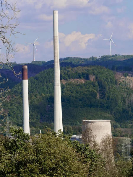 In the foreground a decommissioned coal-fired power plant, in the background wind turbines.