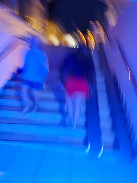 Underpass with a footpath with people blur background. Long luminous underground tunnel and people out of focus background.