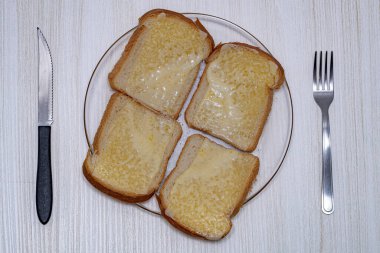 Üstünde erimiş mozzarella peyniri dilimi olan bir somun ekmek.