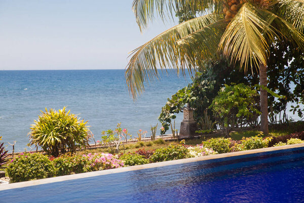 Роскошный бассейн рядом с пляжем. Бассейн с голубой водой у моря. Балийские курорты. Территория отеля у моря.