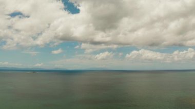 Deniz Burnu. Bulutlu deniz ve gökyüzü. Mercan resifleri ve adaları olan deniz burnu. Tropikal iklim ve Filipinler 'in doğası.