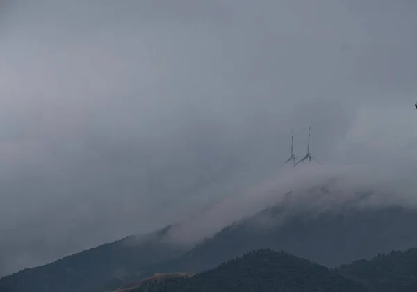 リグーリアの海岸の丘の霧に包まれた風のエネルギーを利用した風力タービン — ストック写真