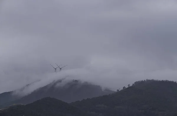 リグーリアの海岸の丘の霧に包まれた風のエネルギーを利用した風力タービン — ストック写真