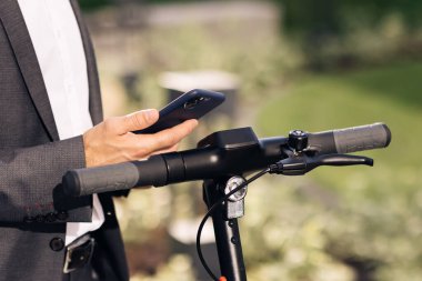 Tanınmayan turist işadamı elektrikli scooter NFC kontaksız dolap kullanıyor. Adam cep telefonu uygulaması kullanarak elektrikli scooter kiralıyor. Kiralık scooter için telefon başvurusu. Ekolojik Şehir Taşımacılığı