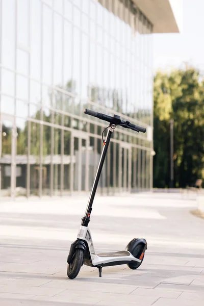 Scooter eléctrico estacionado en una fila en la ciudad. Una fila de alquiler o paseo compartiendo scooter cerca de una concurrida intersección de la ciudad con el tráfico. Movilidad de scooter eléctrico. E-scooter alquiler transporte ecológico — Foto de Stock