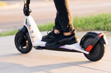 Yakın plan, erkek, elektrikli scooter kullanıyor. Modern ulaşım araçları ve gençler arasında popüler fütürist cihazlar. Çekici adam duruyor, scooter 'a biniyor ve biniyor..