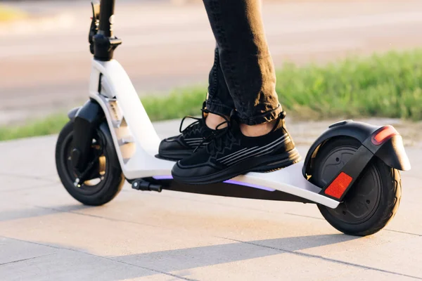 Yakın plan, erkek, elektrikli scooter kullanıyor. Modern ulaşım araçları ve gençler arasında popüler fütürist cihazlar. Çekici adam duruyor, scooter 'a biniyor ve biniyor.. — Stok fotoğraf