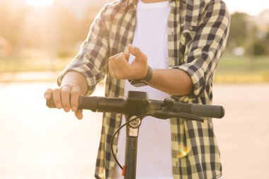 Tanınmayan turist park alanında elektrikli scooter ya da bisiklet kullanır. Akıllı saat uygulaması. Çevre taşımacılığı. Scooter için akıllı telefon uygulaması