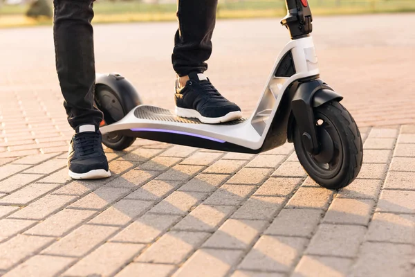 Modern Adam Güneşli Gün 'de elektrikli scooter kullanıyor. İşe elektrikli scooterla giden yetişkin bir adam. Siyah spor ayakkabılı adam elektrikli mobiletle geziyor. Çevre dostu ulaşım — Stok fotoğraf