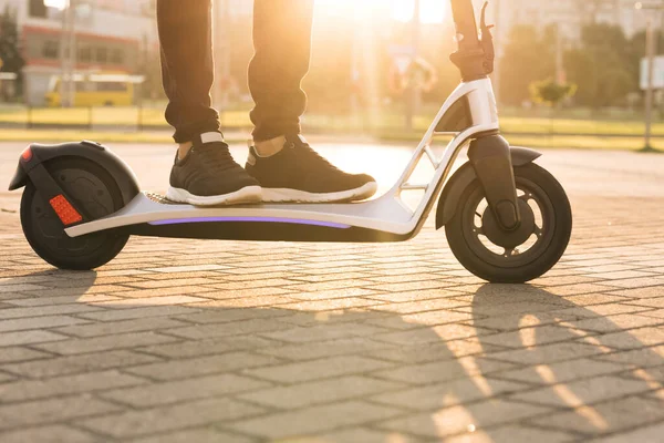 E-scuter călăreț, om plimbare de partajare sau închiriere de transport eco personal. Hipster de sex masculin de echitatie un drum scuter electric pentru a lucra modul modern. Viteză rapidă de conducere transport electric, lumină de dimineață — Fotografie, imagine de stoc