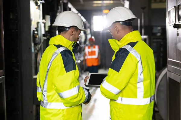 두 중공업 기술자 스탠드 in Pipe Manufacturing Factory, Use Digital Tablet Computer, Have Discussion. 석유 , 가스 , 연료를 운반하는 송유관의 건설을 위한 설비. — 스톡 사진