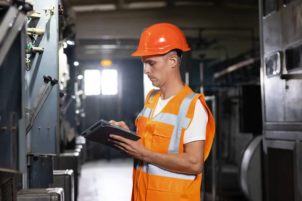 전문적 인 남성 중공업 엔지니어는 안전 조합을 착용하고 태블릿 컴퓨터를 사용 한다. 금속 건축 공장에서 있는 산업 전문가 — 스톡 사진