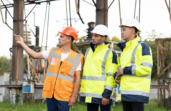 전기 산업, 전기 에너지 생산 개념. 에너지 근로자들은 전선 근처에서 일하는 것에 대해 의논 한다. 발전소에서 공사를 계획하고 있는 특별 봉사자들 — 스톡 사진