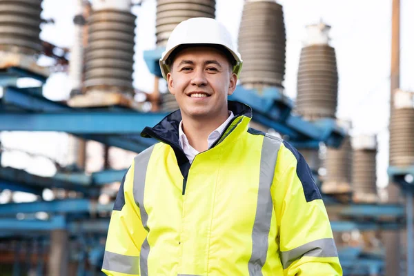 Endüstri insanları. Sürdürülebilir enerji. Asyalı ekoloji işçisinin portresi. Yüksek voltajlı elektrik santralinde duruyor. Teknoloji