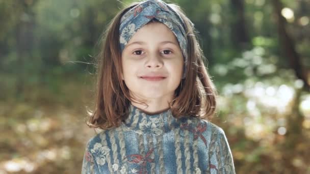 Close-up Face Happy girl in rays of the sun. Girl face in park. Happy face of a child in rays of sun. Child smiles at camera. Beautiful face happy child in park — Stock Video