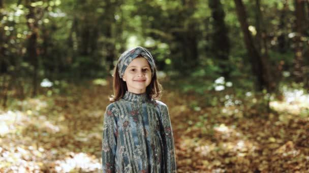 Retrato de uma menina feliz no parque de outono. Criança feliz brincando na floresta amarela alaranjada. Feliz infância. Criança sorri para a câmera. Bela cara criança feliz no parque — Vídeo de Stock