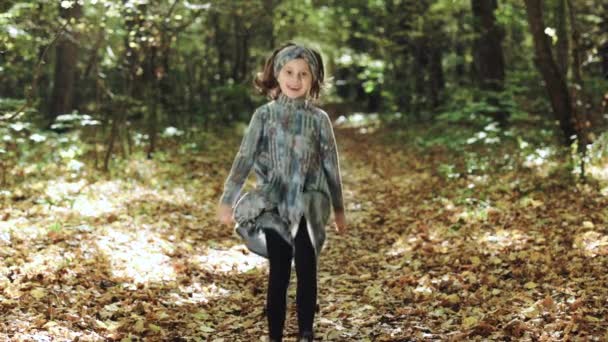 Uma menina estudante corre pelo parque. Miúdos educados. Retrato crianças felizes correndo perto da floresta de outono e olhando para a câmera. Os miúdos divertem-se ao ar livre. Conceito de infância — Vídeo de Stock