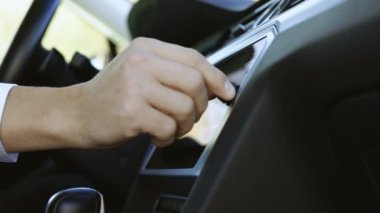 Şoför telsize döndü. Müzik dinlemek için hoparlörün sesini parmaklarıyla ayarlıyorum. Otomobil ses düğmesine bas