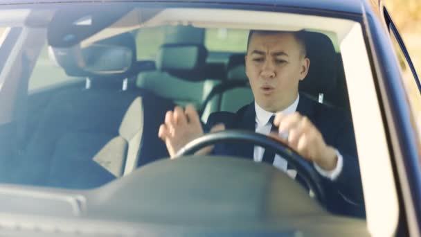 Arg mogen man sitter i bilen och bankar med händerna på ratten. Affärsman som kör bil med negativa känslor. Problem, trafik, bråttom — Stockvideo