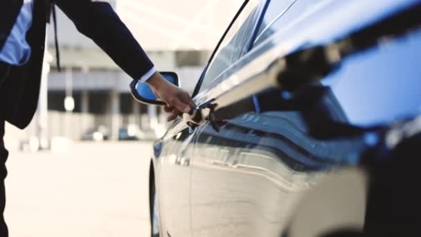 Udany biznesmen w garniturze idzie do swojego czarnego luksusowego elektrycznego samochodu i dostaje się do jego kabiny. Nierozpoznany biznesmen dojeżdżający do pracy. Pewny siebie facet w garniturze jest w drodze do pracy. — Wideo stockowe