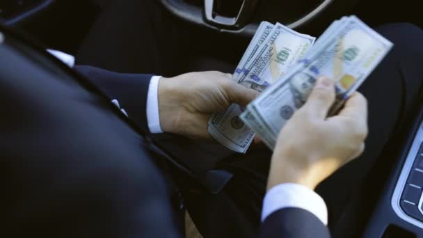 Un exitoso hombre de negocios celebrando la victoria sosteniendo dinero en efectivo en las manos del vehículo. Dólares de diferentes denominaciones. Hombre contando billetes de dólar sentado en coche de lujo. — Vídeos de Stock