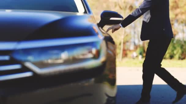 Bonito empresário que caminha até o carro elétrico preto. Abre a porta e entra. Pessoas e transporte. Sucesso. Riqueza. Eco transporte amigável — Vídeo de Stock