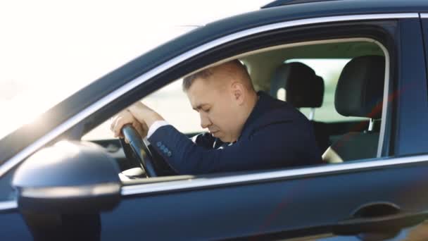 Frustrado cansado jovem homem sentado carro na cidade à luz do sol. Sinto-me com raiva de depressão. Homem de negócios inclinando a cabeça no volante enquanto se sente cansado depois de andar de longa distância — Vídeo de Stock