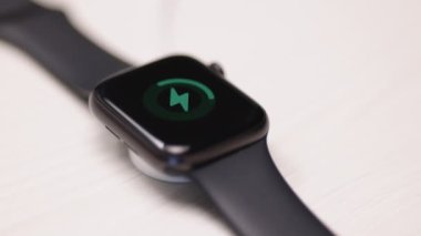 Akıllı adam şarj ediliyor. Akıllı saatin kablosuz şarjla şarj olmasına yakın çekim. Kablosuz teknoloji kavramı. 4k çözünürlükte çekiliyor