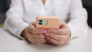 Cep telefonu kullanan kişinin elleri. Moda sosyal medya mesajlaşması cep telefonu sohbeti. Evdeki oturma odasında akıllı telefon kullanan ve mesaj yazan bir kız. Genç bir kadının elinin yakın çekimi..