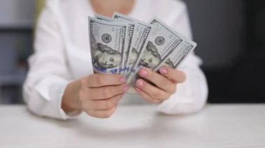 Başarılı bir kadın nakit parayı kontrol ediyor. Yakından bir iş kadını 100 dolarlık banknotlar tutuyor. Tanınmayan bir kadın elinde dolarlarla eğleniyor. Para ödeme kavramı