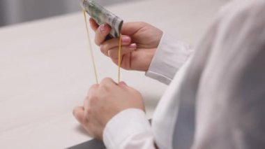 Kadın eli kravatı dolar banknotlarını sarıp sarmaladı. 100 dolarlık banknotlar ve sarı lastik bant. Kauçuk bant, nakit ödemelerin sembolü. Tanık rüşveti, yasa dışı maaş. Yozlaşma. Vergi hilesi