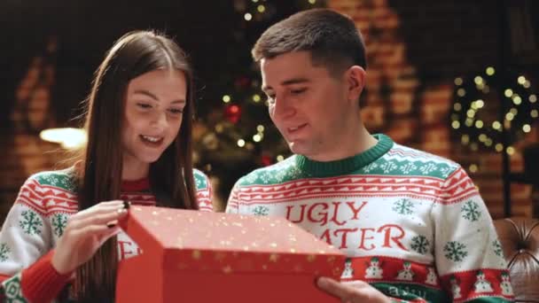 Szczęśliwy mężczyzna robi prezent świąteczny dla ukochanej kobiety. Kobieta jest zaskoczona i podekscytowana po otwarciu otrzymanego pudełka z prezentami. Pojęcie wakacji, romans, niespodzianka, e-commerce, Boże Narodzenie, Cud świąteczny — Wideo stockowe