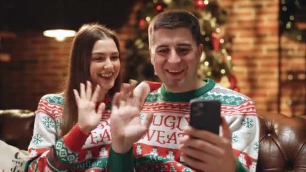 Couple en chandails d'hiver enregistrer la vidéo du Nouvel An salutations pour les amis et la famille à la maison. Famille utilisant un téléphone intelligent parler à la famille félicite Joyeux Noël par application de vidéoconférence. — Video