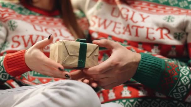 Männliche Hände verschenken Geschenke in weihnachtlichem Geschenkpapier mit grüner Schleife an weibliche Hände. Person im Geschenkkarton. Konzept Familienurlaub, perfekte Weihnachten, Neujahr, Feiern — Stockvideo