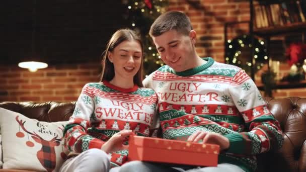 自宅でお祝いの休日を祝うボーイフレンドと面白い冗談を楽しんで笑って驚きのセクシーな下着でプレゼントを開くクリスマスギフトの女性。4kのスローモーション. — ストック動画