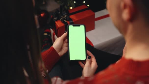 Coppia caucasica utilizzando lo smartphone per la videochiamata di Natale con schermo verde mock up. Natale, festività e tecnologie della comunicazione — Video Stock